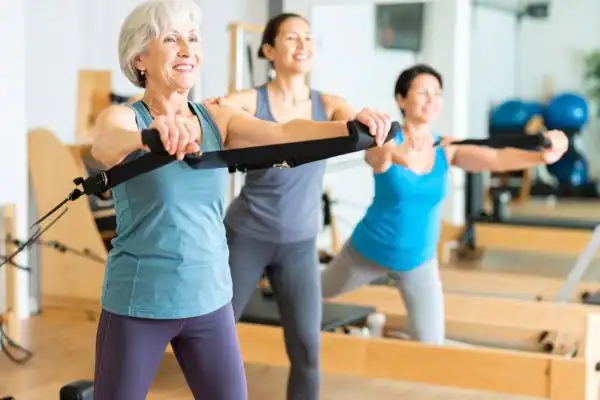 Toning Arms After 60: Empowering Womens Fitness Through Effective Weight Training 2 older woman doing weight training East Grinstead and resistance in the gym to tone upper arms