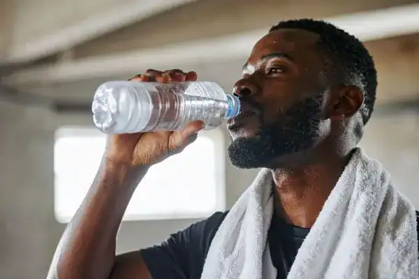 Image of man drinking water to improve hydration East Grinstead after work out.